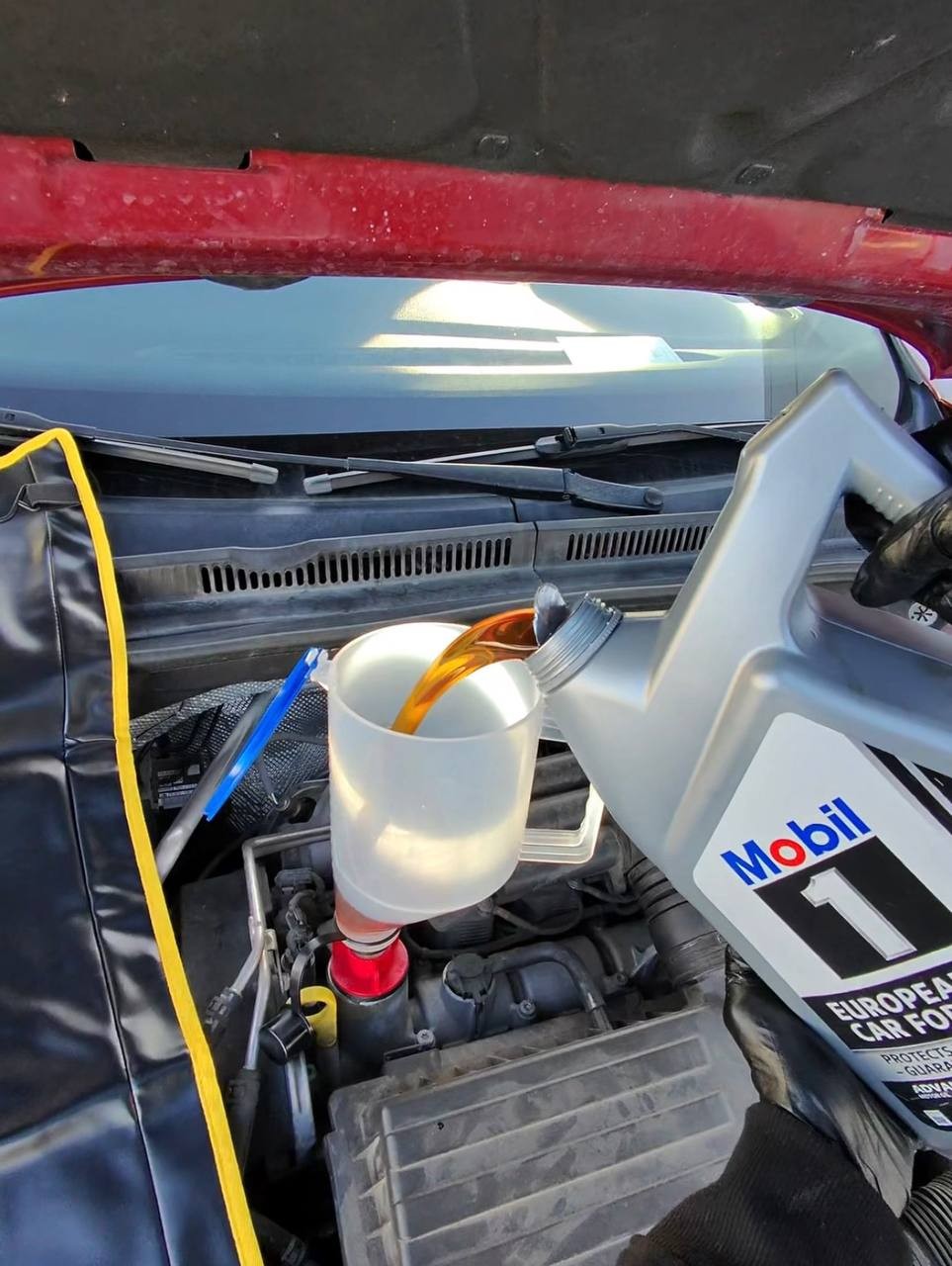 Pouring engine oil through a funnel during a driveway oil change
